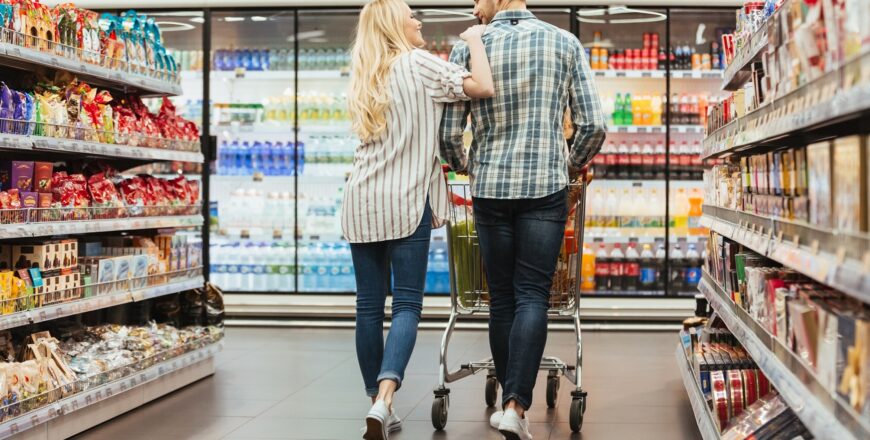 Back view of a smiling couple walking with a trolley at the supermarket